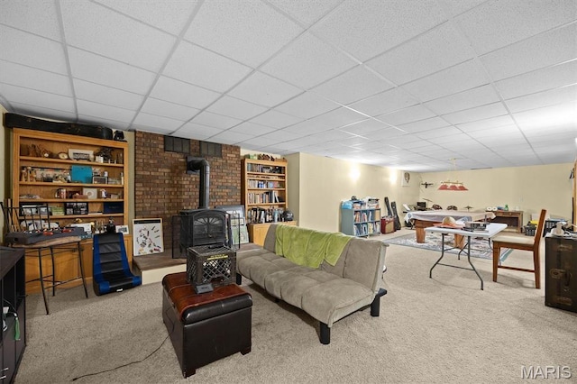 living room featuring a wood stove, carpet floors, and a drop ceiling