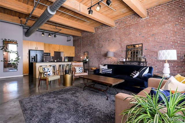 901 Washington Ave Unit 411, Saint Louis, MO 63101 - living area featuring a high ceiling, brick wall, concrete flooring, baseboards, and track lighting