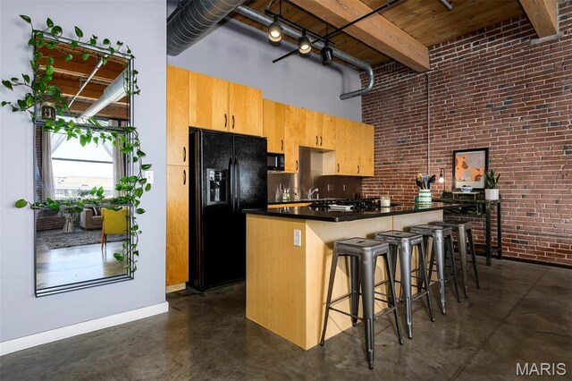 901 Washington Ave Unit 411, Saint Louis, MO 63101 - kitchen with black appliances, finished concrete flooring, brick wall, a high ceiling, and dark countertops