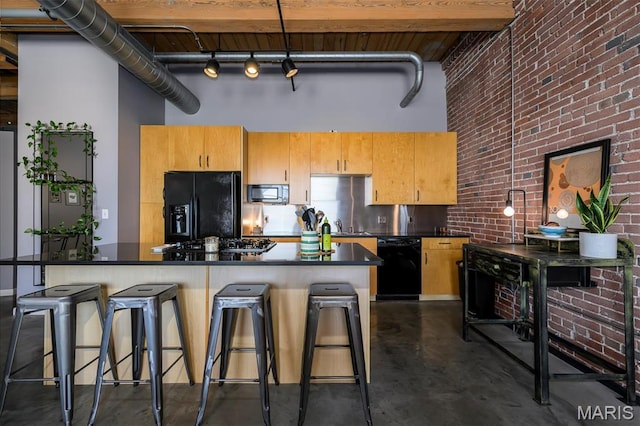 901 Washington Ave Unit 411, Saint Louis, MO 63101 - kitchen with black appliances, a high ceiling, finished concrete floors, brick wall, and dark countertops