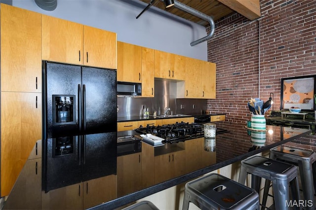 901 Washington Ave Unit 411, Saint Louis, MO 63101 - kitchen featuring black appliances, dark countertops, decorative backsplash, a high ceiling, and a breakfast bar area