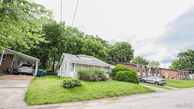 view of front facade with a front lawn, concrete driveway, and an attached carport