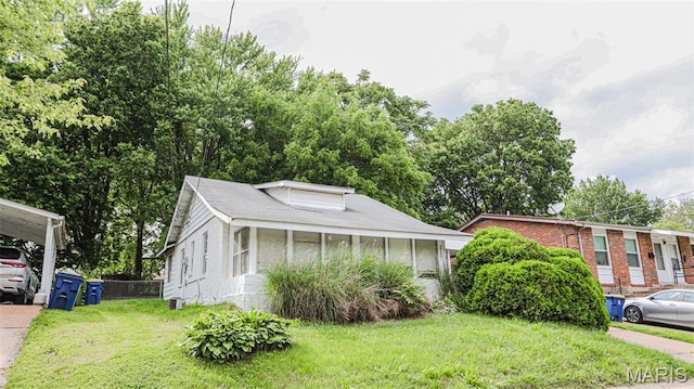 view of front of home with a front lawn, a carport, and brick siding