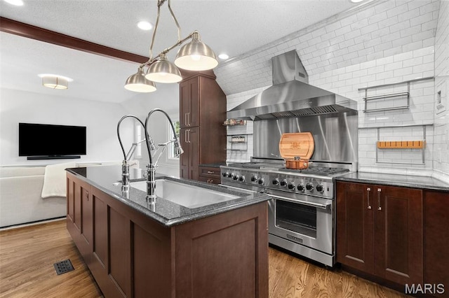 2 Northcote Rd, Saint Louis, MO 63144 - kitchen with stainless steel stove, wall chimney exhaust hood, a sink, decorative backsplash, and dark stone countertops
