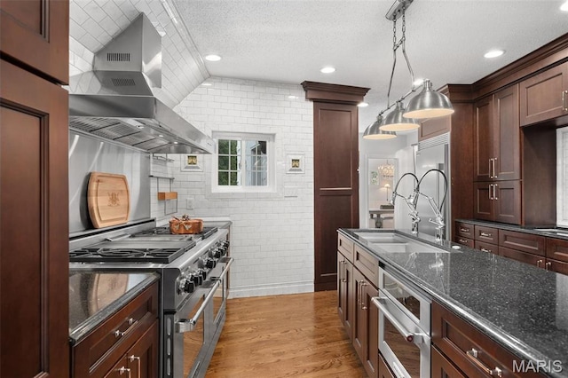 2 Northcote Rd, Saint Louis, MO 63144 - kitchen featuring wall chimney range hood, a sink, appliances with stainless steel finishes, recessed lighting, and dark stone counters
