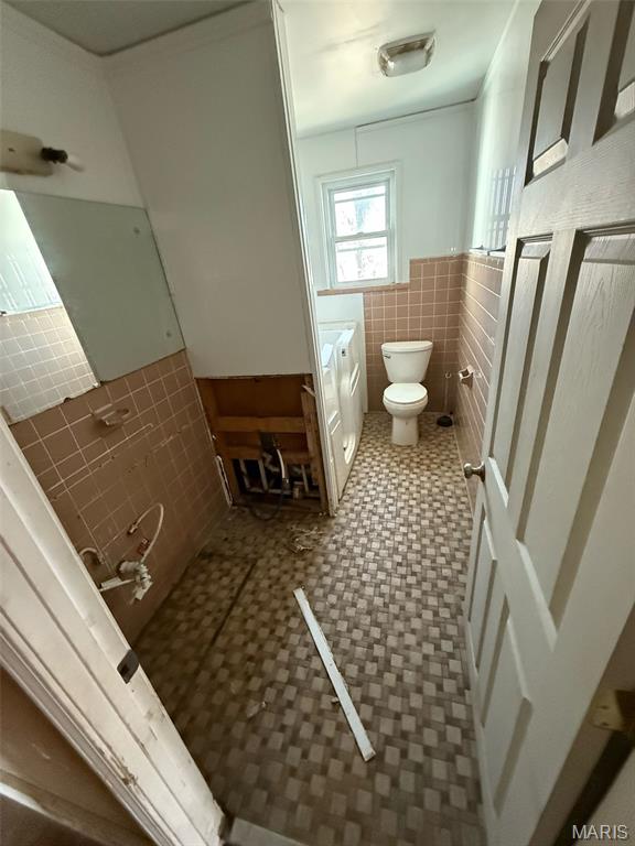 6966 Front St, Barnhart, MO 63012 - bathroom with tile walls, toilet, vanity, a wainscoted wall, and tile patterned floors