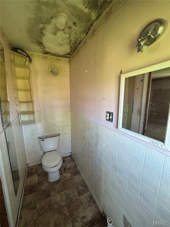 6966 Front St, Barnhart, MO 63012 - bathroom with tile walls, toilet, wainscoting, and stone finish floors