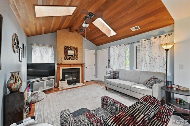 living area with a skylight, vaulted ceiling, a fireplace, wooden ceiling, and wood finished floors