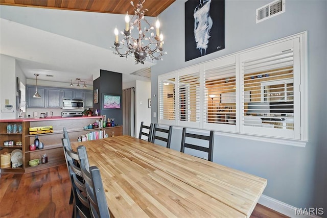 dining room with a chandelier, dark wood finished floors, vaulted ceiling, and baseboards