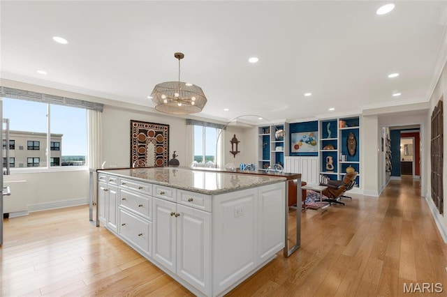 900 S Hanley Rd Unit 15E, Clayton, MO 63105 - kitchen with ornamental molding, a chandelier, white cabinetry, a kitchen island, and baseboards