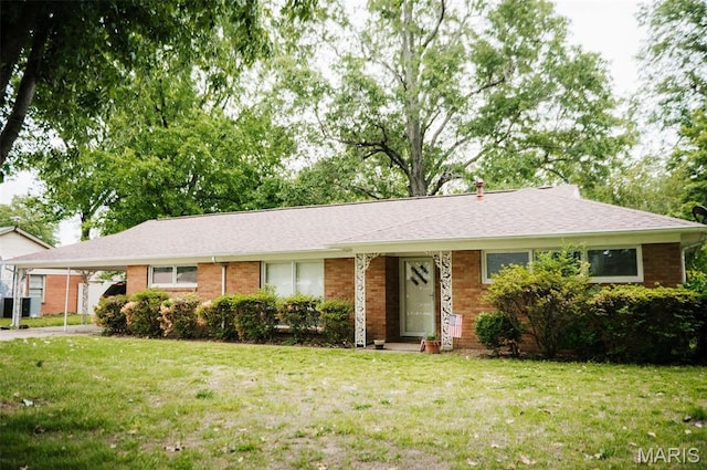 single story home with a front lawn, an attached carport, and brick siding