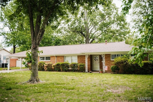 single story home featuring a front yard, driveway, brick siding, and central AC