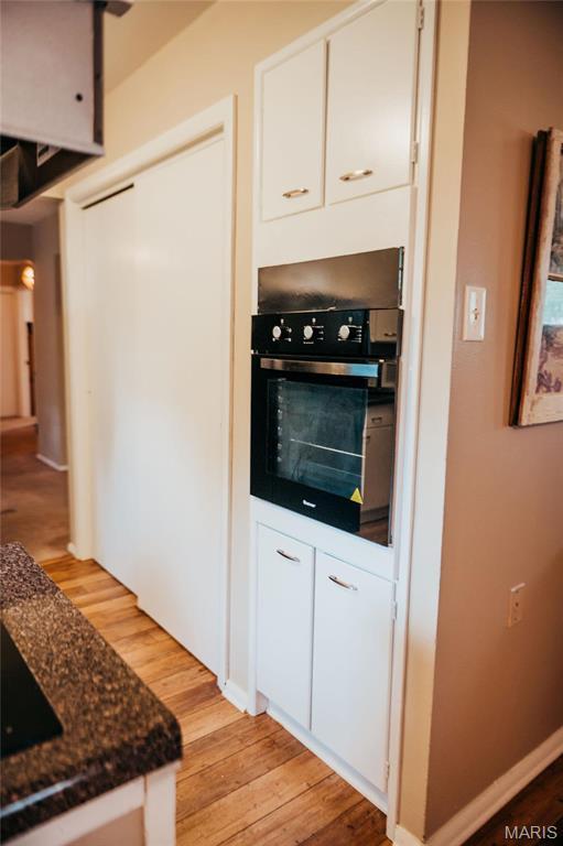 kitchen featuring wall oven, light wood-style flooring, and white cabinetry