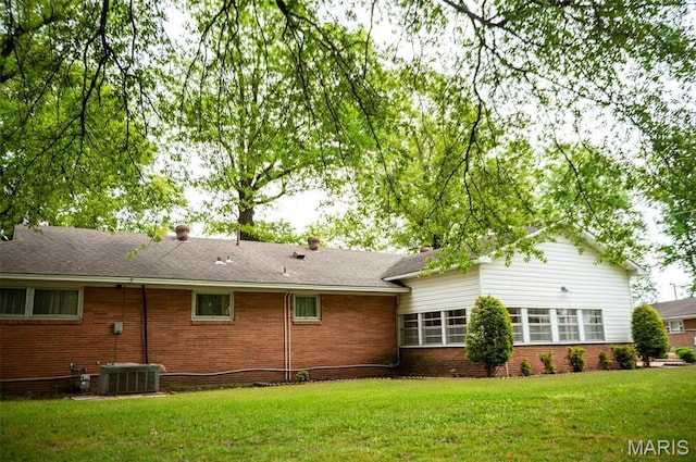 back of property with brick siding, a yard, and central AC unit