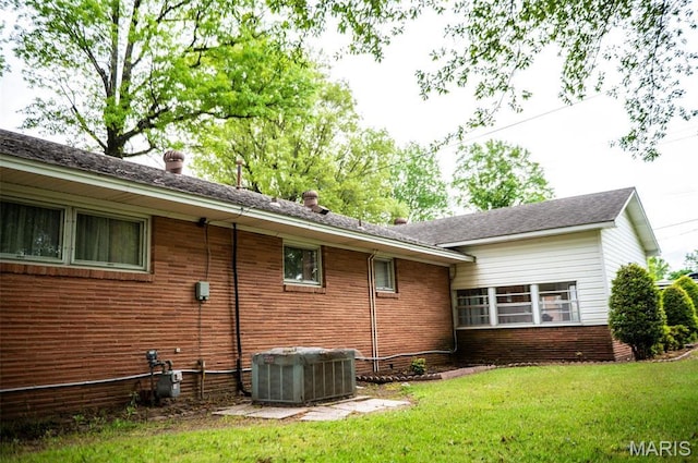 view of home's exterior featuring central air condition unit, a lawn, and brick siding