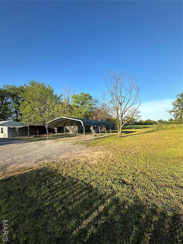 549 E Outer Rd, Sikeston, MO 63801 - view of grassy yard featuring a detached carport and gravel driveway