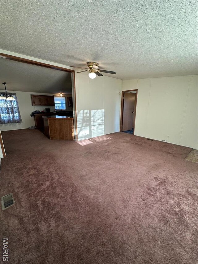 549 E Outer Rd, Sikeston, MO 63801 - unfurnished living room with dark colored carpet, ceiling fan, and a textured ceiling