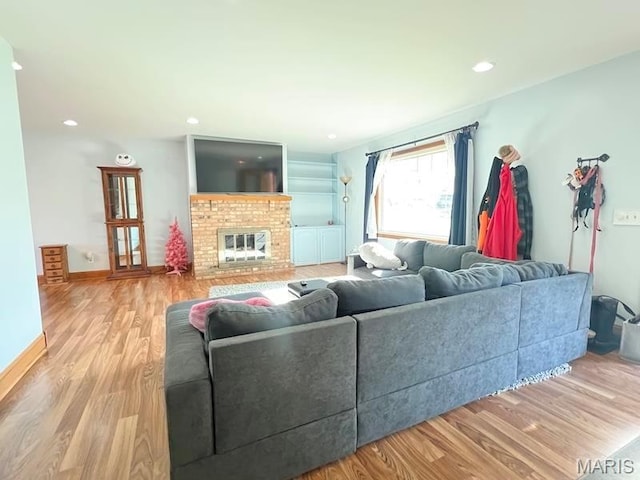living area featuring wood finished floors, a fireplace, recessed lighting, and baseboards
