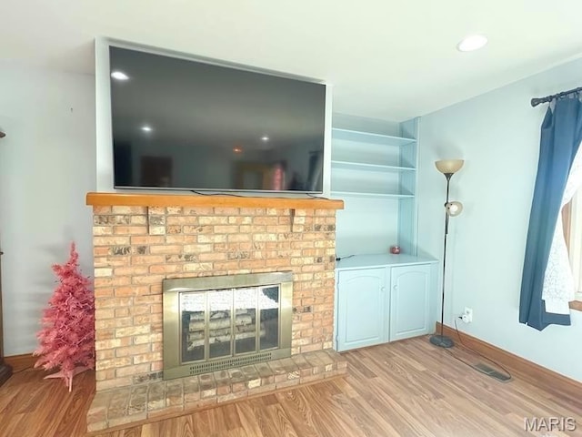 unfurnished living room featuring a fireplace, wood finished floors, and baseboards
