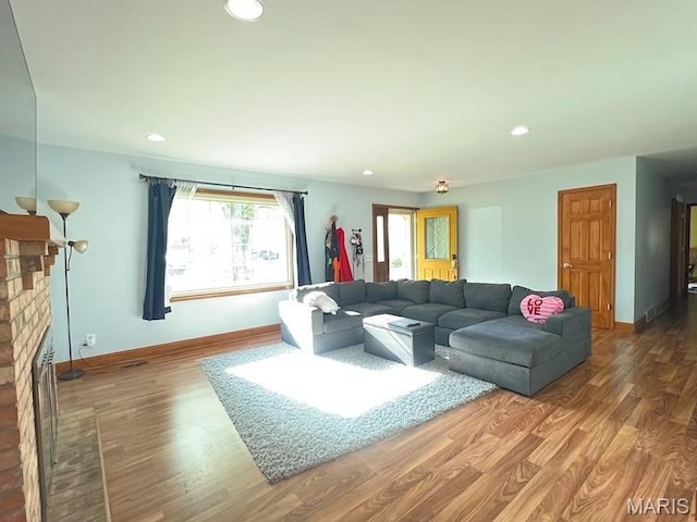 living room with a fireplace, wood finished floors, baseboards, and recessed lighting