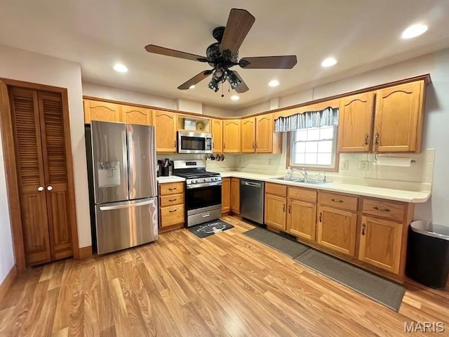 kitchen featuring stainless steel appliances, a sink, light wood-style floors, light countertops, and recessed lighting