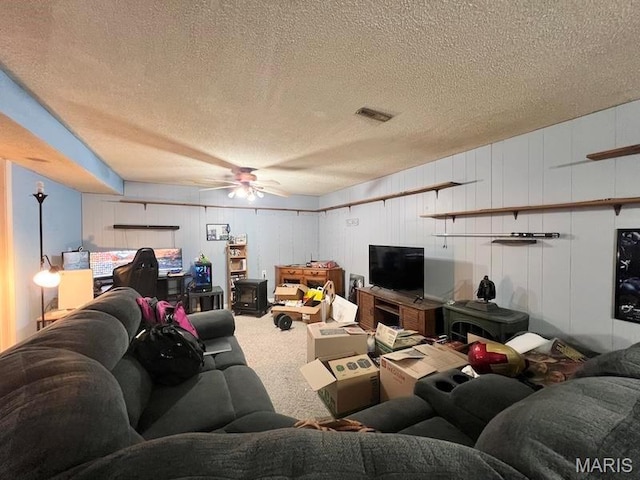 carpeted living area with a ceiling fan and a textured ceiling