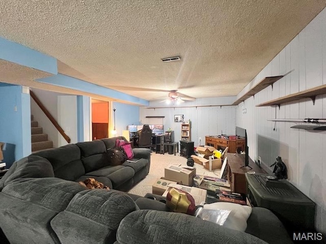 carpeted living area featuring ceiling fan, stairs, and a textured ceiling