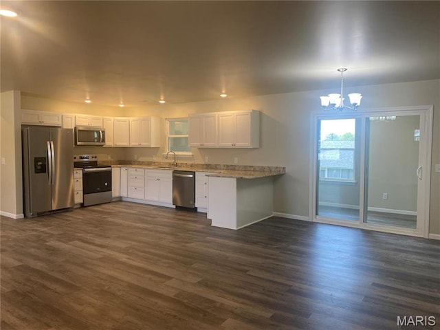kitchen featuring appliances with stainless steel finishes, a sink, baseboards, and a chandelier
