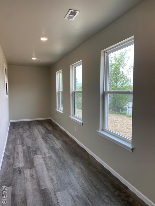 empty room with dark wood-style flooring, baseboards, and recessed lighting