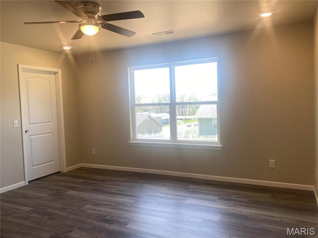 empty room featuring dark wood-style flooring, baseboards, and ceiling fan