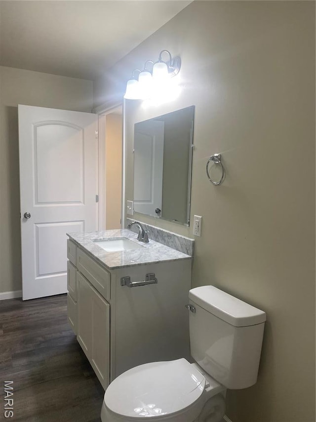 bathroom featuring wood finished floors, toilet, vanity, and baseboards
