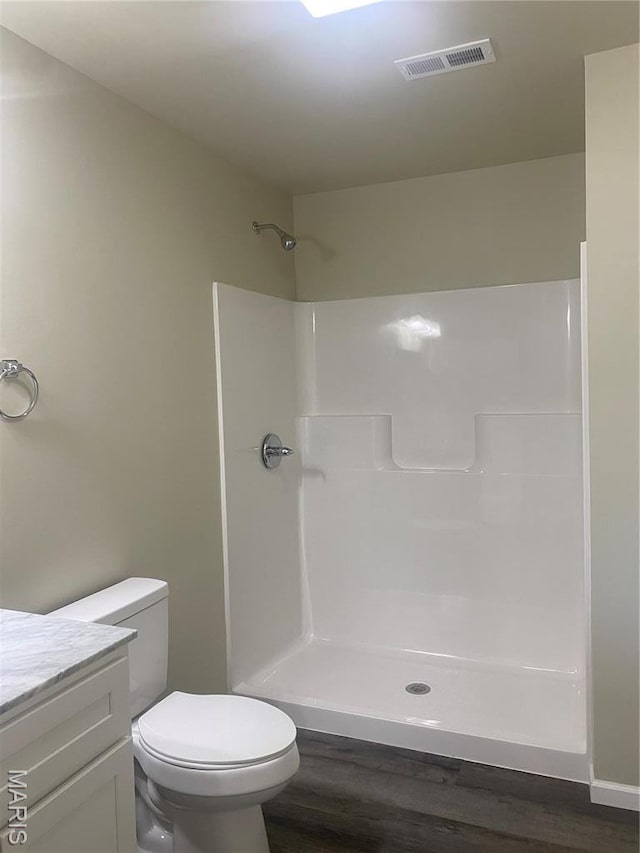 bathroom with wood finished floors, a shower, toilet, and vanity