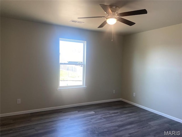 empty room with dark wood finished floors, a ceiling fan, and baseboards