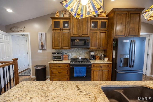 1753 Rue Marseilles, Bonne Terre, MO 63628 - kitchen with stainless steel microwave, refrigerator with ice dispenser, black gas range oven, vaulted ceiling, and decorative backsplash