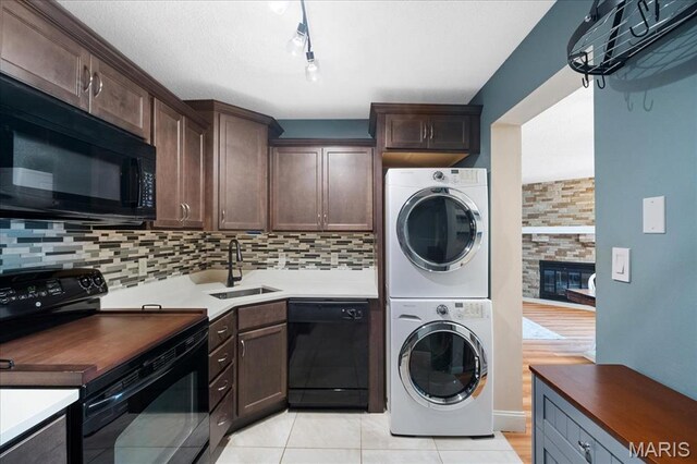 9005 Cardinal Ter, Saint Louis, MO 63144 - washroom featuring estacked washer and dryer, light tile patterned flooring, a fireplace, and rail lighting