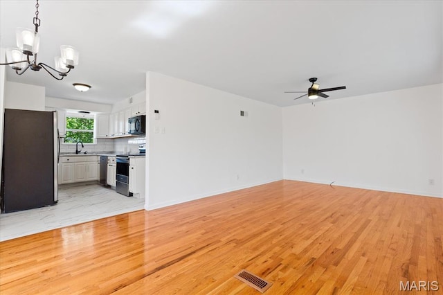 656 Beatrice Ave, Saint Louis, MO 63125 - unfurnished living room featuring a chandelier, light wood-style flooring, a ceiling fan, a sink, and baseboards