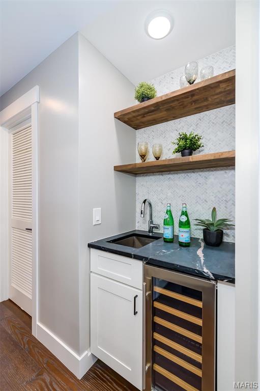 122 N Central Ave Unit A, Saint Louis, MO 63105 - indoor wet bar with wine cooler, backsplash, dark wood-style flooring, and baseboards