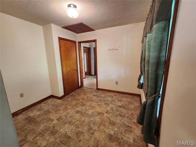 4028 Mcmasters Ave, Hannibal, MO 63401 - unfurnished room featuring a textured ceiling, baseboards, attic access, and stone finish floors