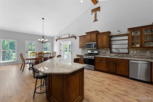 220 Cuivre Point Ln, Moscow Mills, MO 63362 - kitchen with stainless steel appliances, a sink, light wood-style floors, tasteful backsplash, and high vaulted ceiling