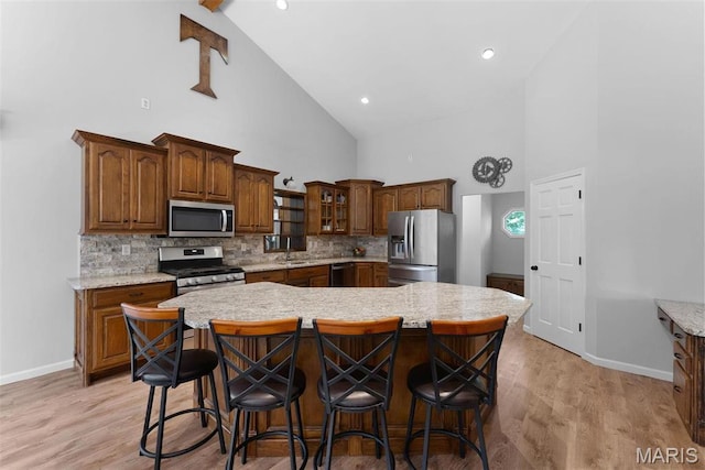 220 Cuivre Point Ln, Moscow Mills, MO 63362 - kitchen with stainless steel appliances, high vaulted ceiling, baseboards, a breakfast bar, and backsplash