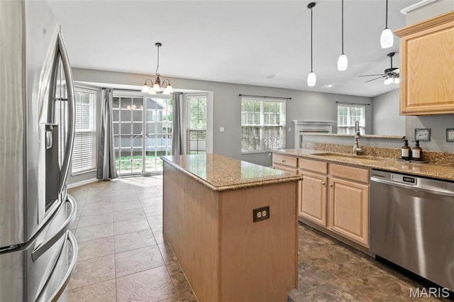 kitchen featuring stainless steel appliances, light brown cabinets, a sink, ceiling fan, and a kitchen island