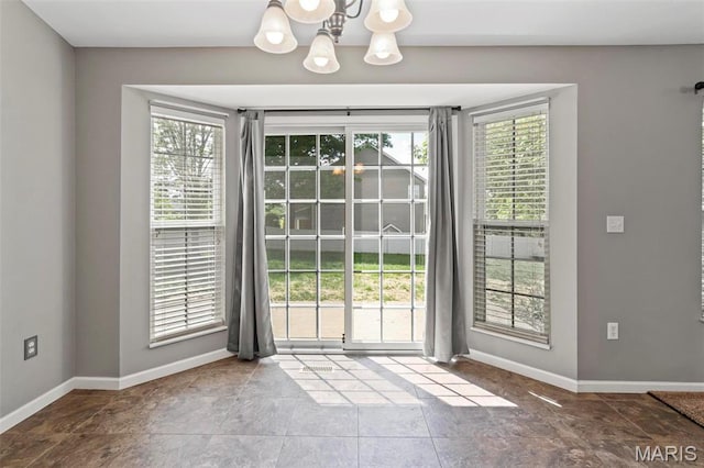 doorway with a chandelier and baseboards
