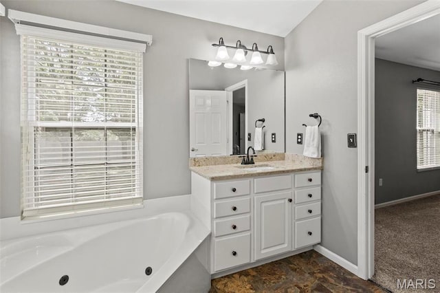 full bath featuring a jetted tub, vanity, and baseboards