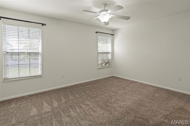 carpeted spare room featuring baseboards and a ceiling fan