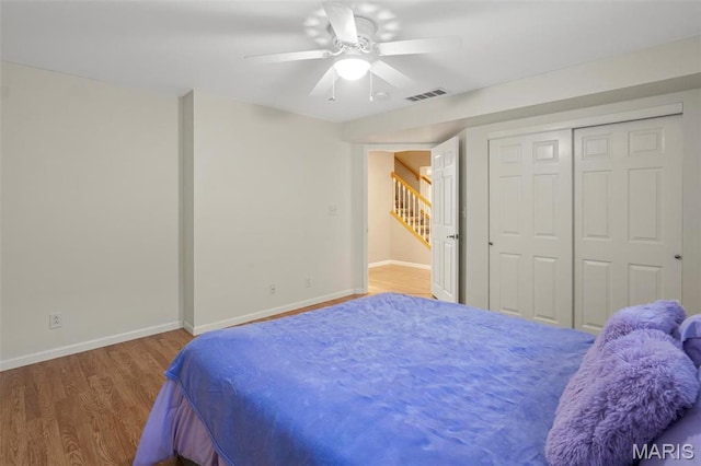 bedroom featuring wood finished floors, baseboards, a ceiling fan, and a closet