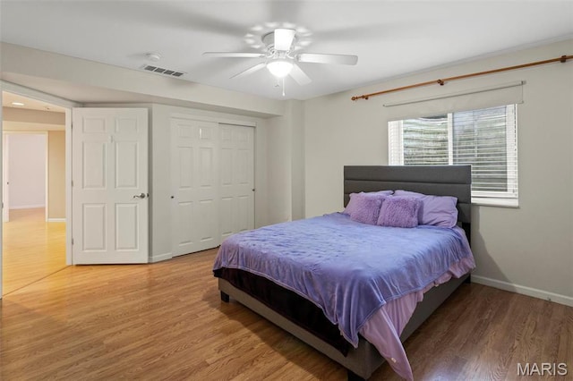 bedroom featuring baseboards, wood finished floors, a closet, and a ceiling fan