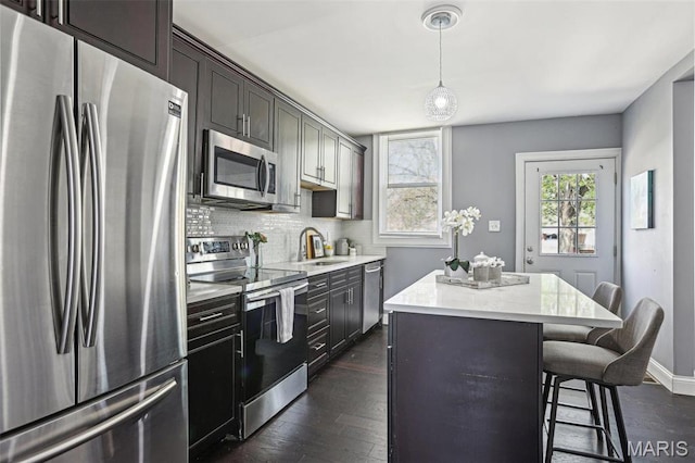 5327 W Ave, Saint Louis, MO 63116 - kitchen with appliances with stainless steel finishes, a sink, a center island, tasteful backsplash, and a kitchen breakfast bar