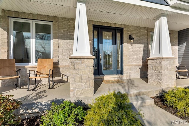 doorway to property with a porch and stone siding