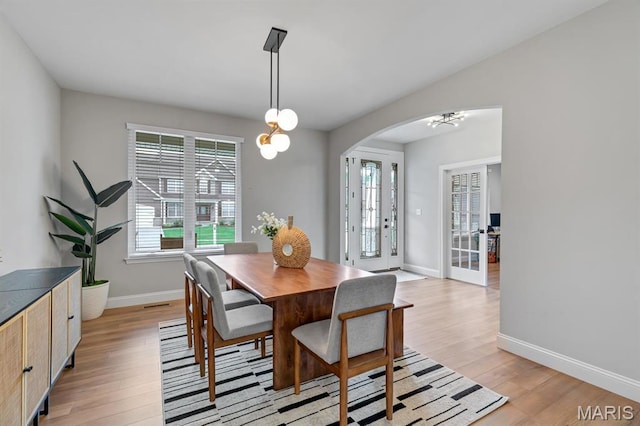 215 Everett Creek Ct, Lake St Louis, MO 63367 - dining room featuring arched walkways, light wood-type flooring, baseboards, and a chandelier