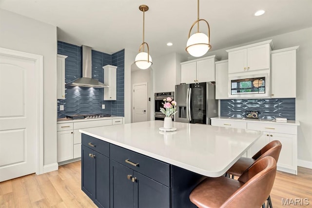 215 Everett Creek Ct, Lake St Louis, MO 63367 - kitchen featuring stainless steel appliances, wall chimney exhaust hood, decorative backsplash, white cabinets, and a center island